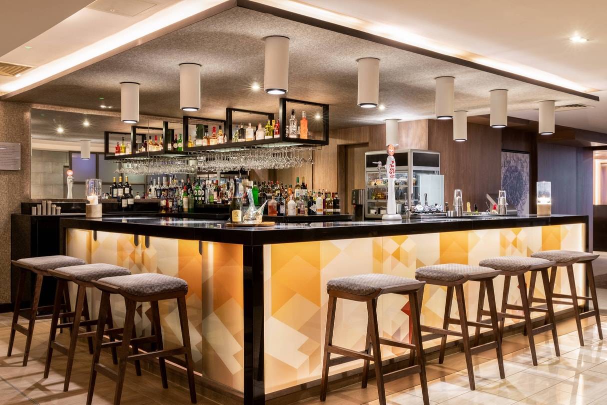 Modern AC Hotel bar with illuminated front for VIP receptions and networking events.