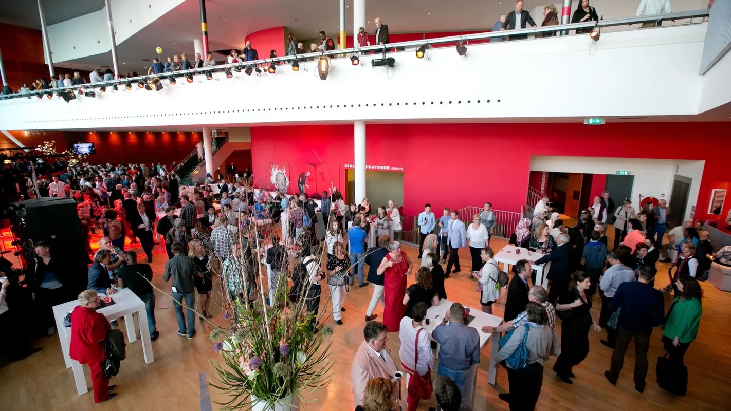 Networking reception in Rhine Foyer at New Luxor Theater with multi-level atrium.