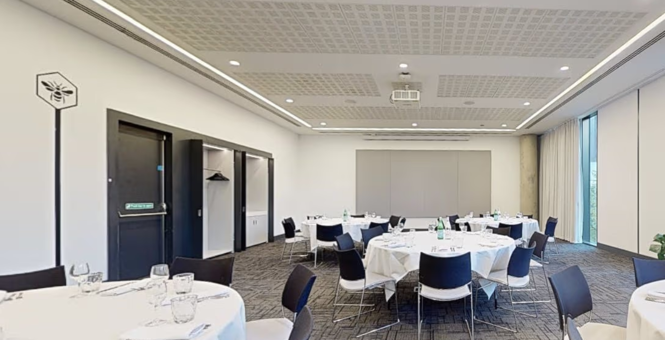 Modern meeting space in INNSIDE Manchester with round tables for events and natural light.