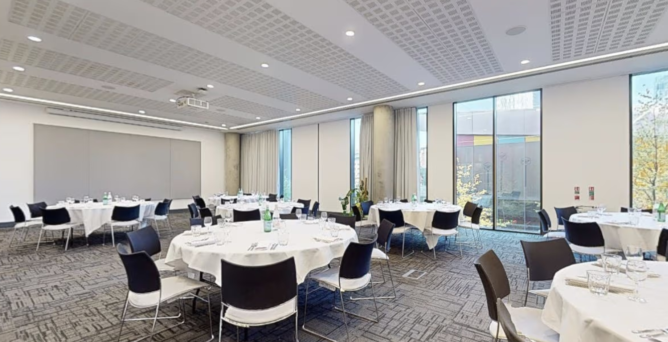 Modern event space in INNSIDE Manchester, featuring elegant round tables and natural light.