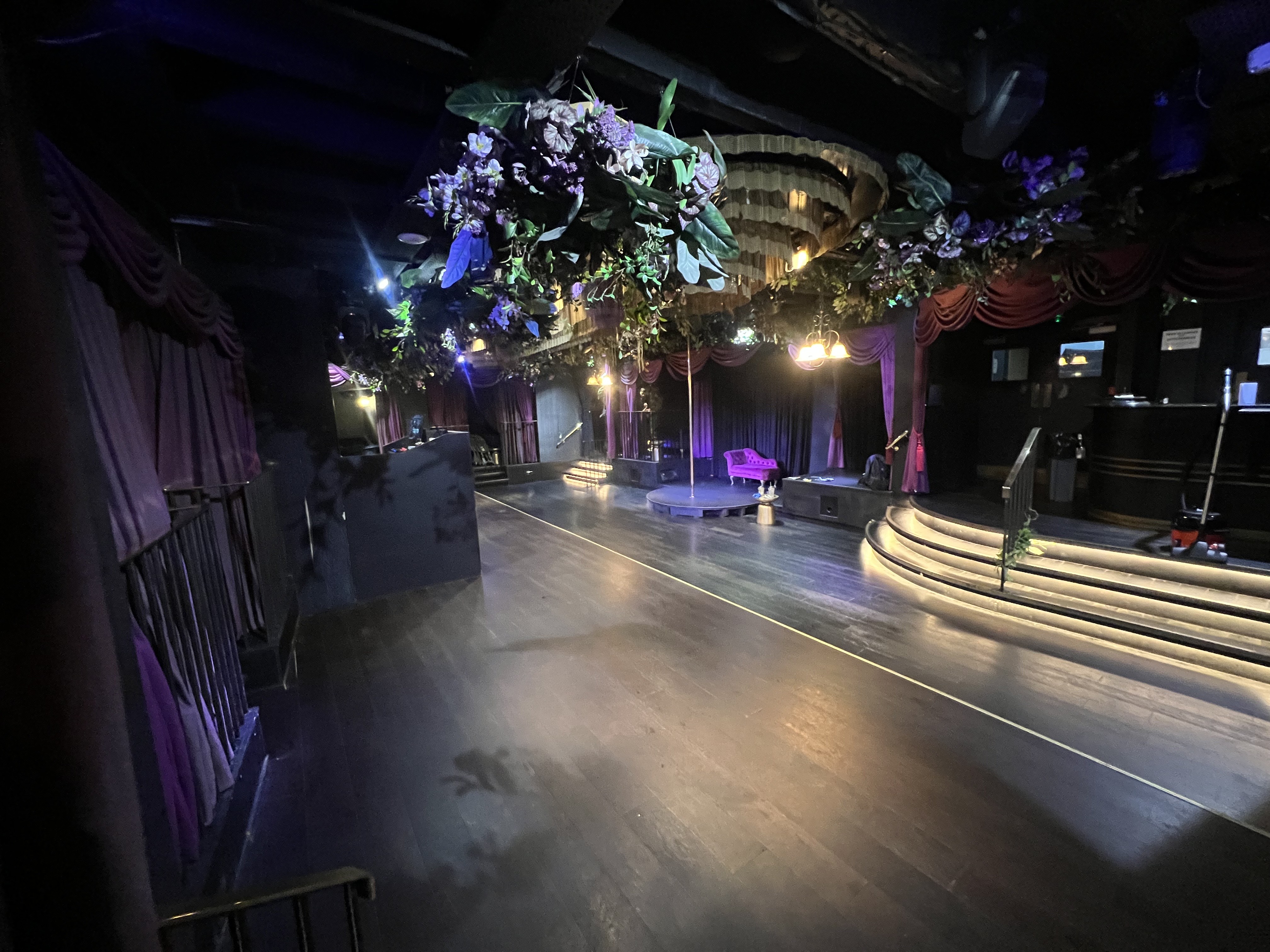 Mood-lit Soho venue with tiered stage and floral decor for VIP activations and brand launches.