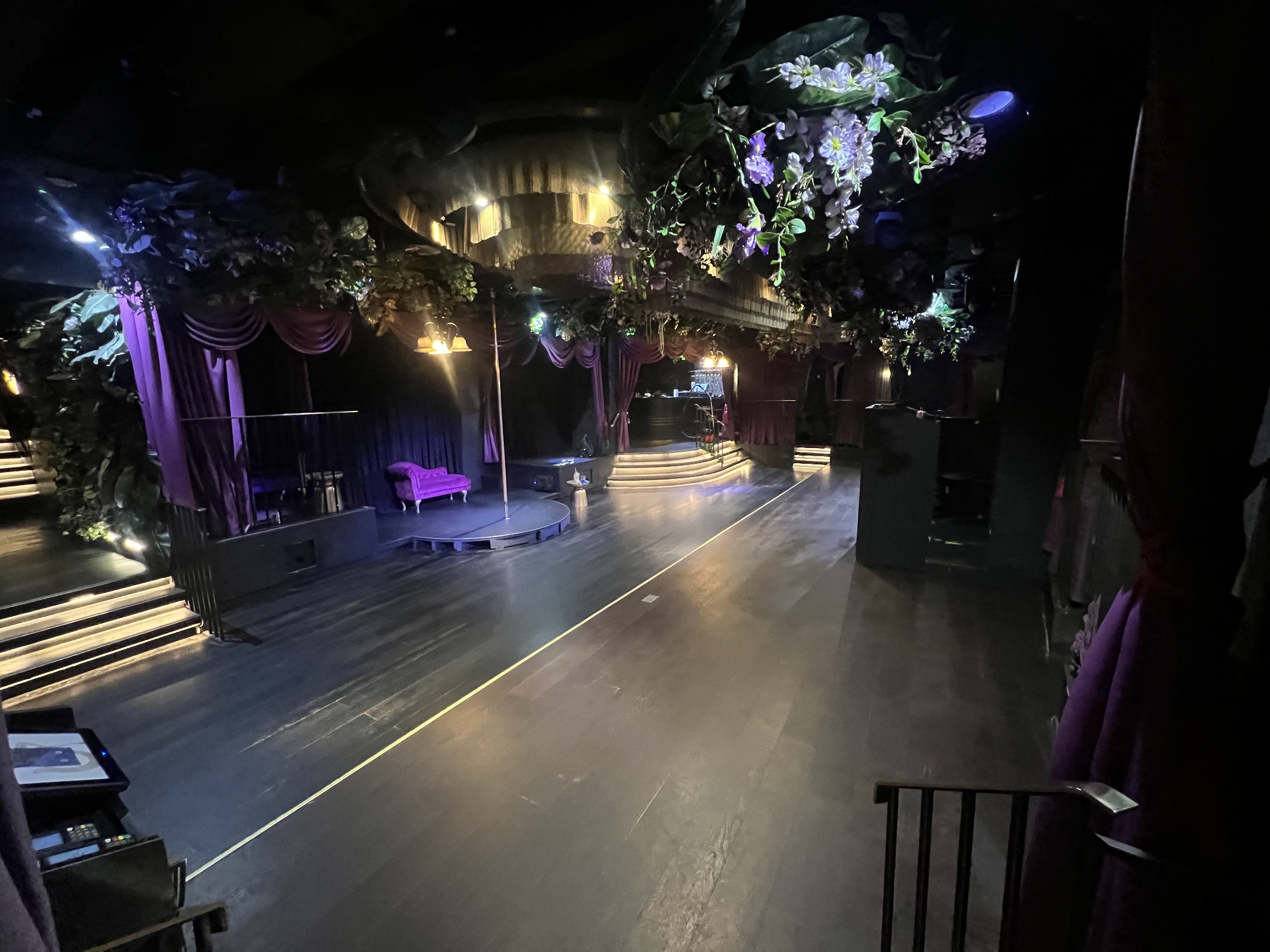 Mood-lit Soho venue with stage and floral decor for gala or experiential activation event.