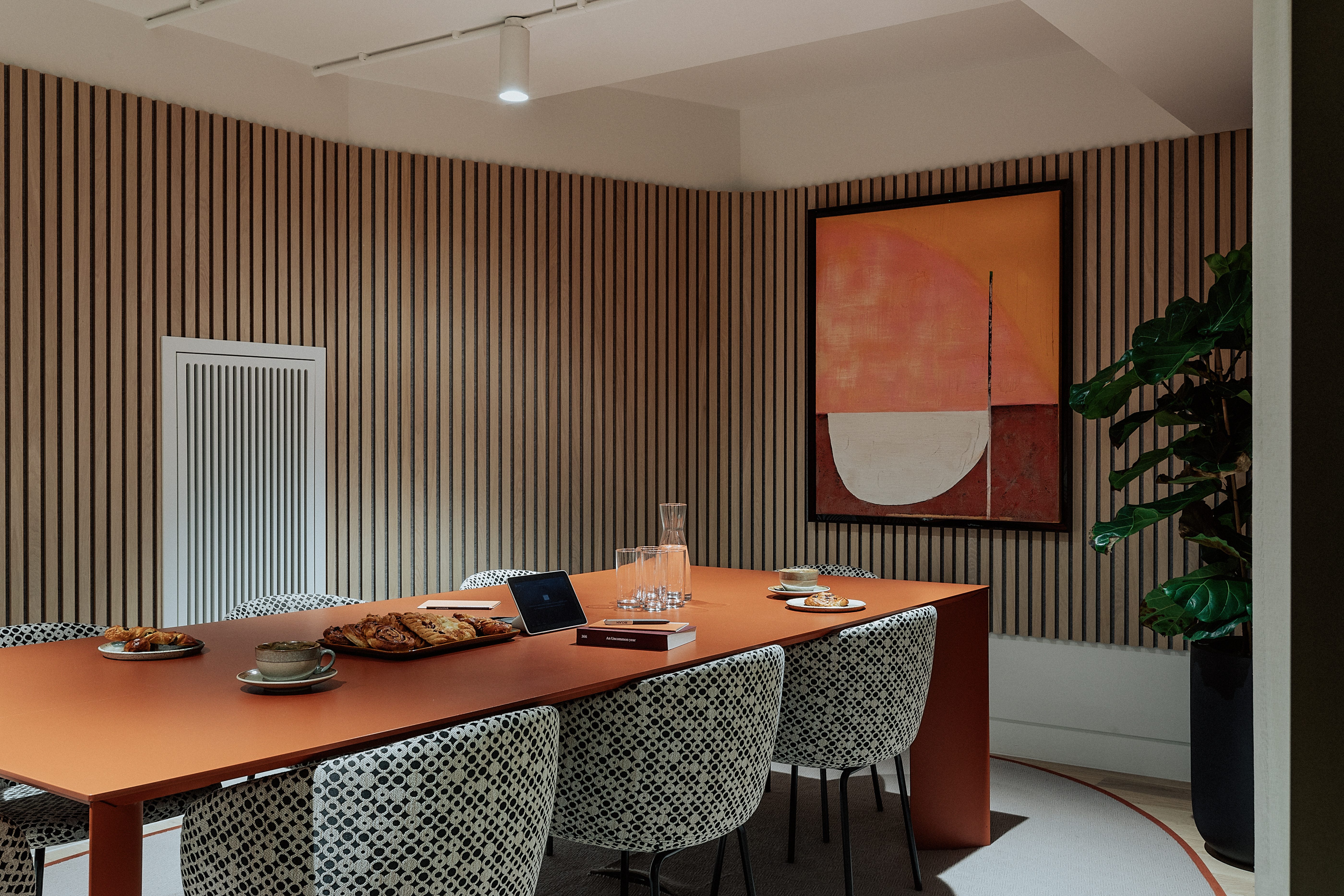 Modern meeting room with orange table, ideal for collaborative gatherings and networking.