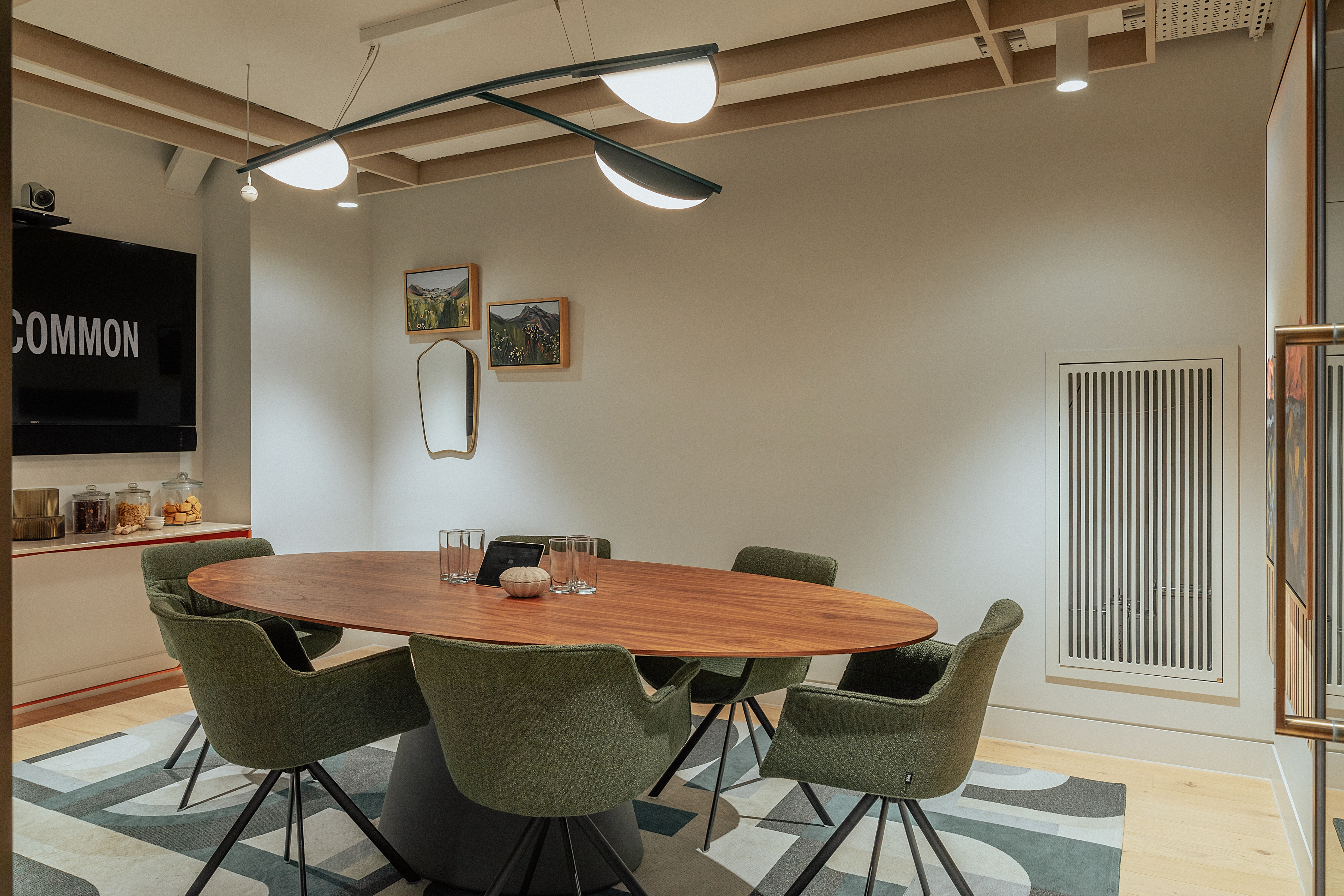 Modern meeting room with oval table and green chairs, perfect for creative brainstorming sessions.