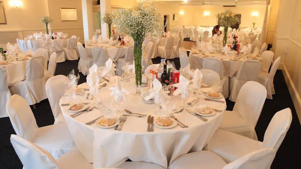 Elegant banquet hall setup with floral centerpieces for weddings or corporate events.