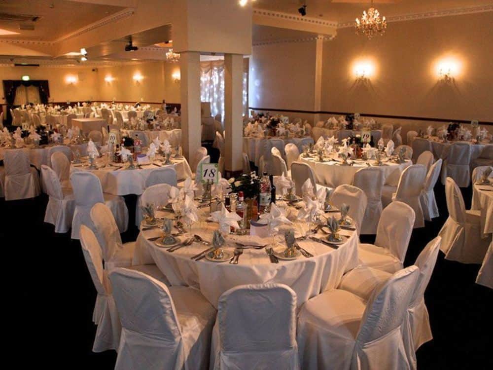 Elegant banquet hall setup for weddings and formal events with white linen tables.