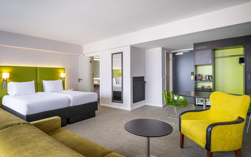 Modern hotel suite with two beds for business travelers and events in Brussels.