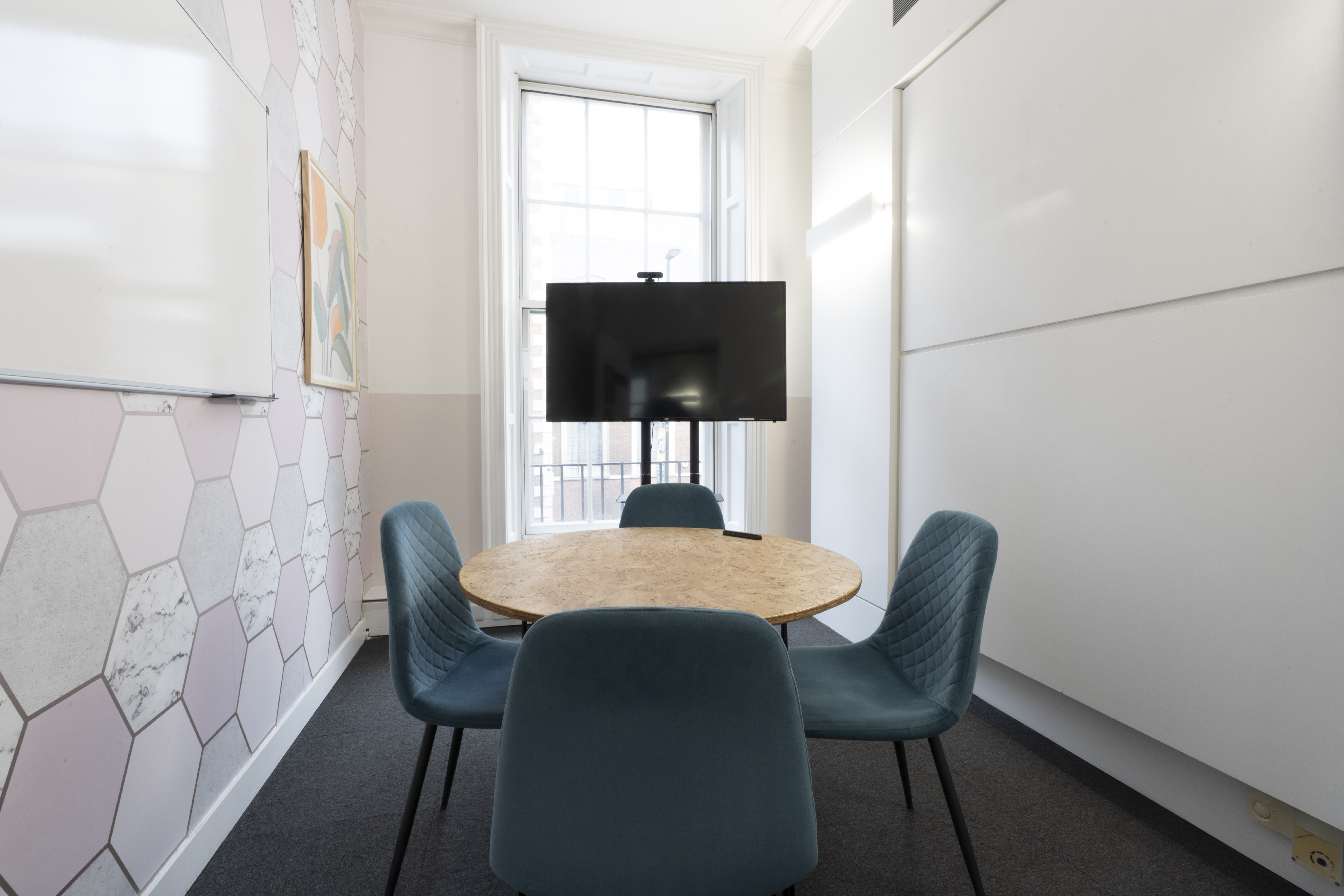 "Modern meeting room with hexagonal wall at Runway East for collaboration and presentations."