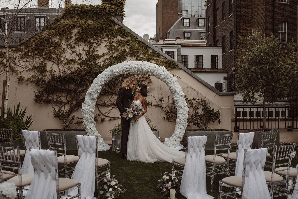 Outdoor wedding ceremony with floral arch at John Newsom-Davis Suite, 41 Portland Place.