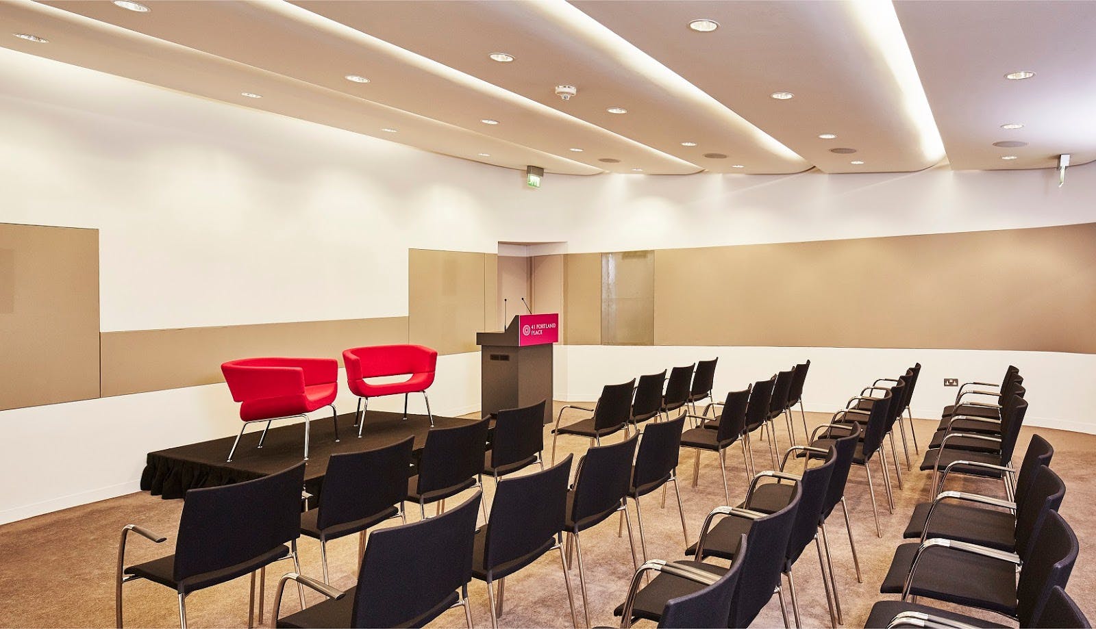 Modern event space at John Newsom-Davis Suite with red chairs for panel discussions.