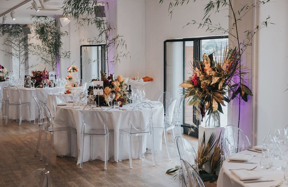Elegant wedding venue with round tables, floral centerpieces, and modern decor.