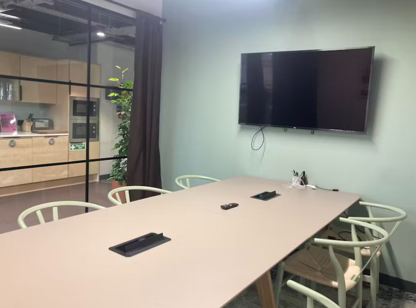 Modern meeting room in Runway East London Bridge with sleek conference table and greenery.