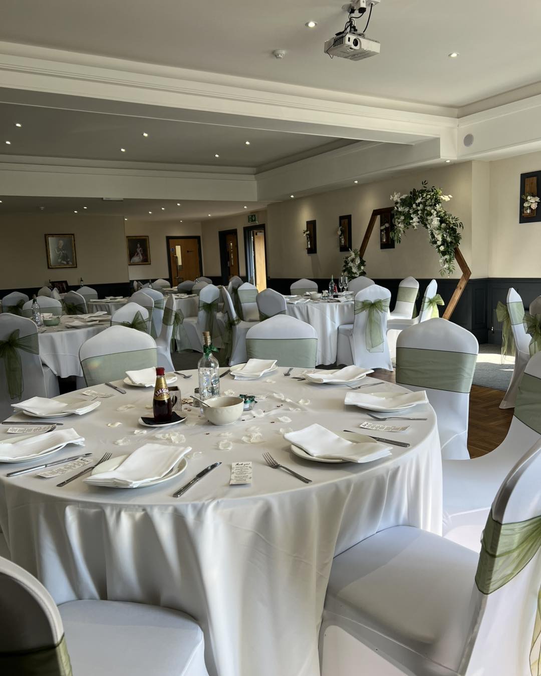 Wedding banquet at The Mill House with sage green floral arch, elegant reception setup.