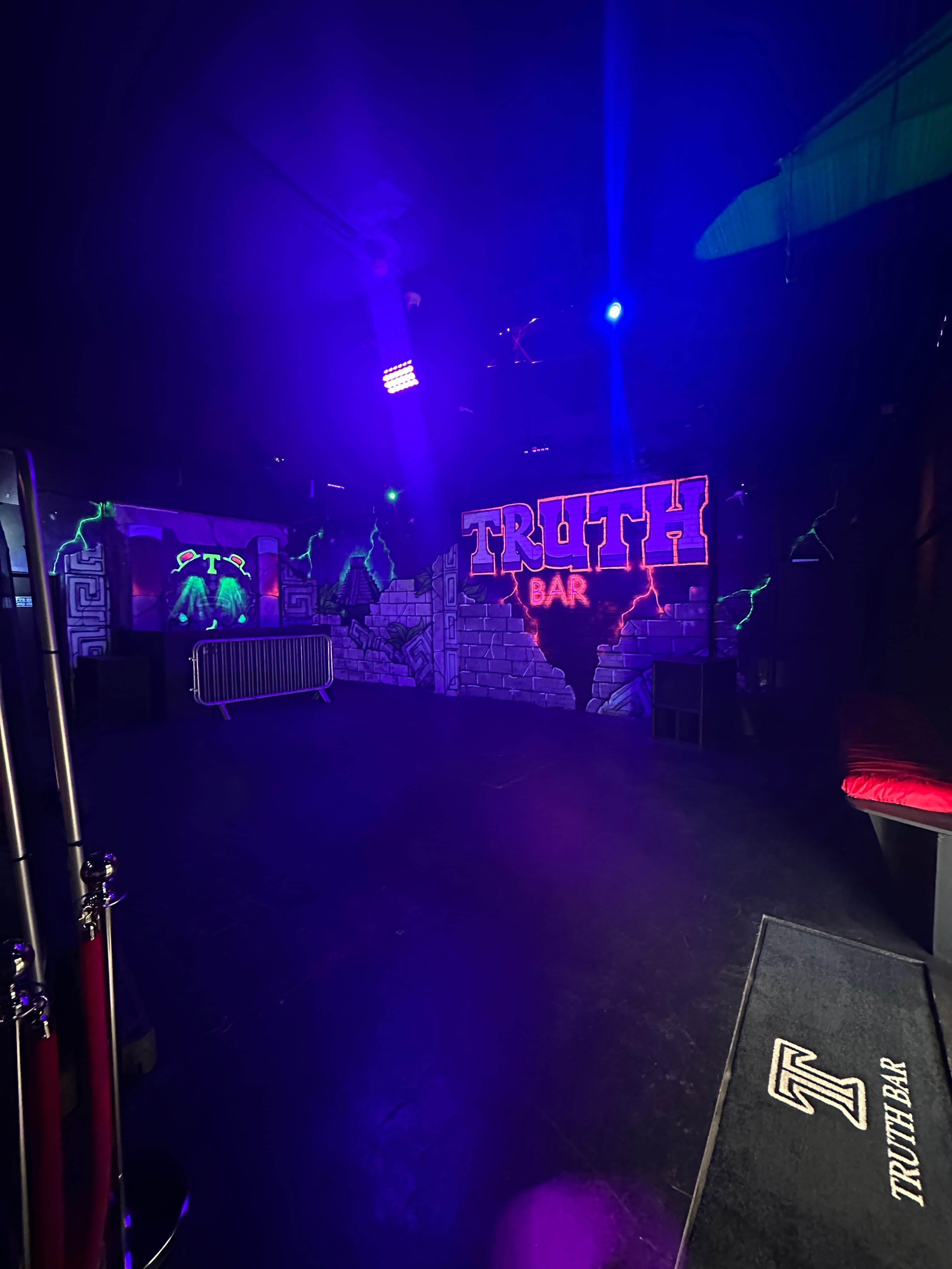 Truth Bar LDN: High-energy nightclub event space with neon signage and blacklight décor.