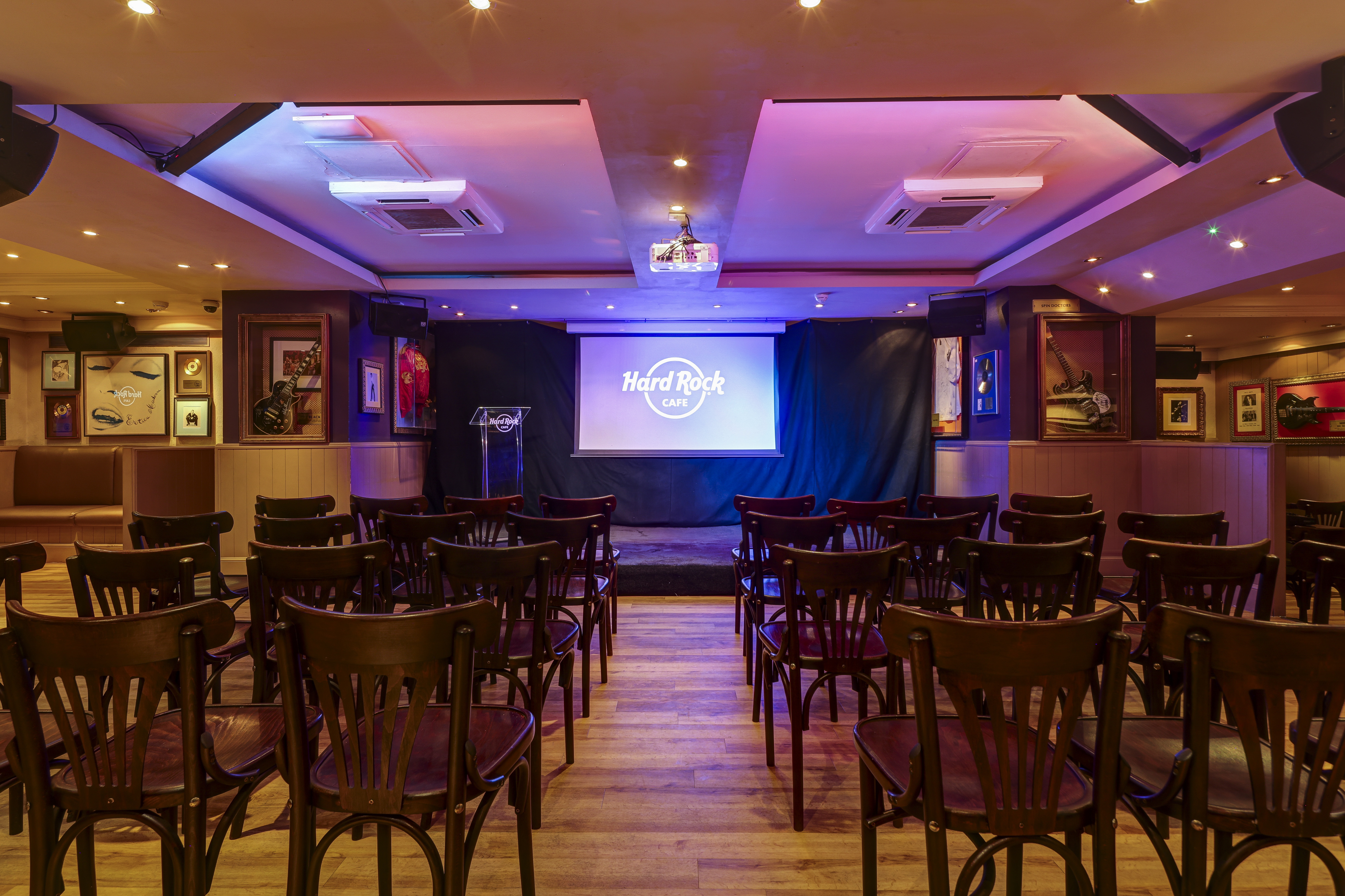 "Meetings at Hard Rock Cafe London with wooden chairs and projector screen for presentations."