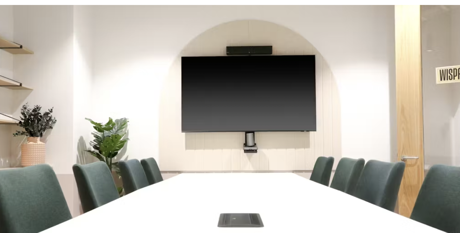 Modern meeting room in Runway East Birmingham with sleek table and green chairs.