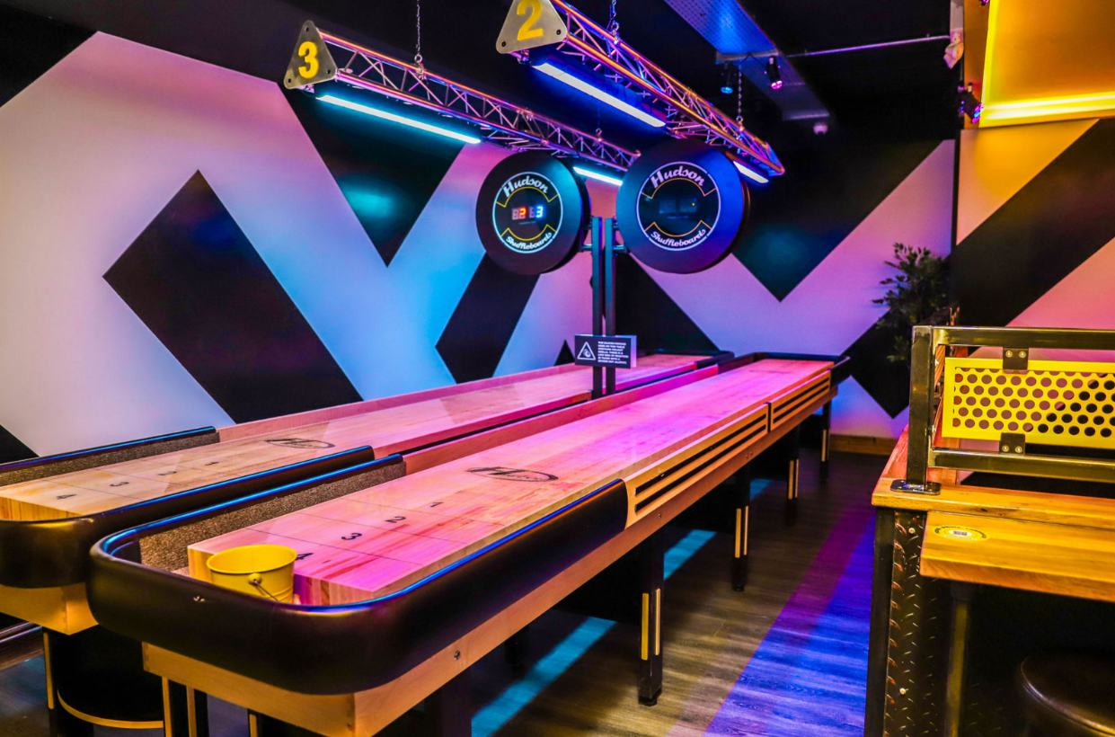 Vibrant shuffleboard event space with neon lights, ideal for networking and team-building.