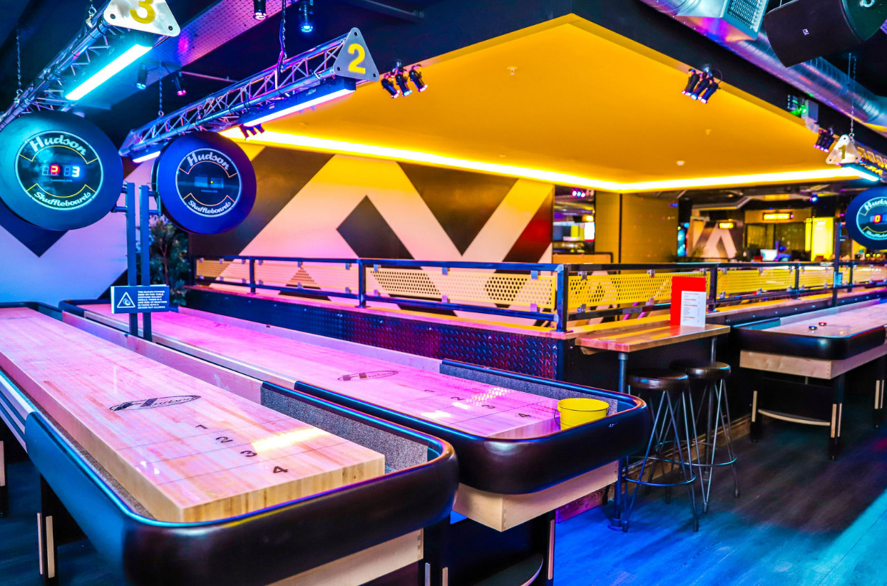 Vibrant shuffleboard lanes in The Glide Zone at King Pins, ideal for corporate events or gatherings.