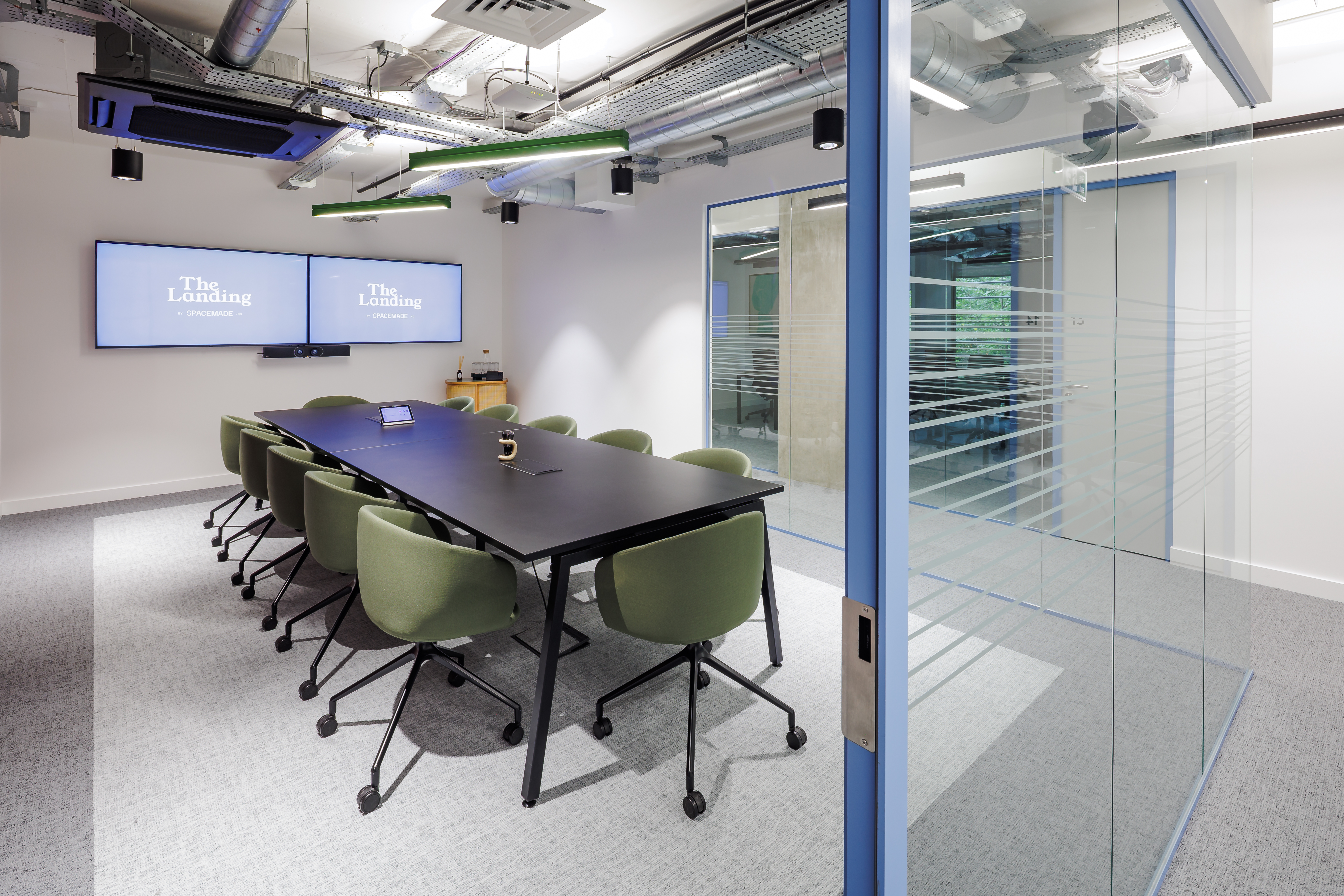 Modern Gibbon Meeting Room with sleek table and green chairs for collaborative conferences.
