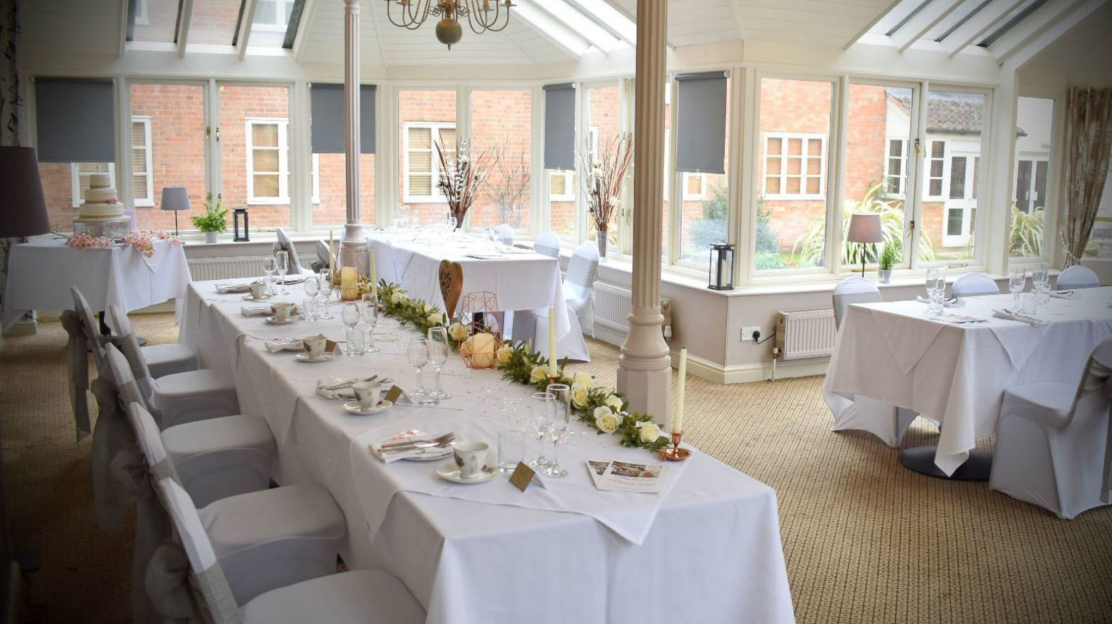 Sun-drenched conservatory banquet hall for micro-wedding and corporate event meetings.