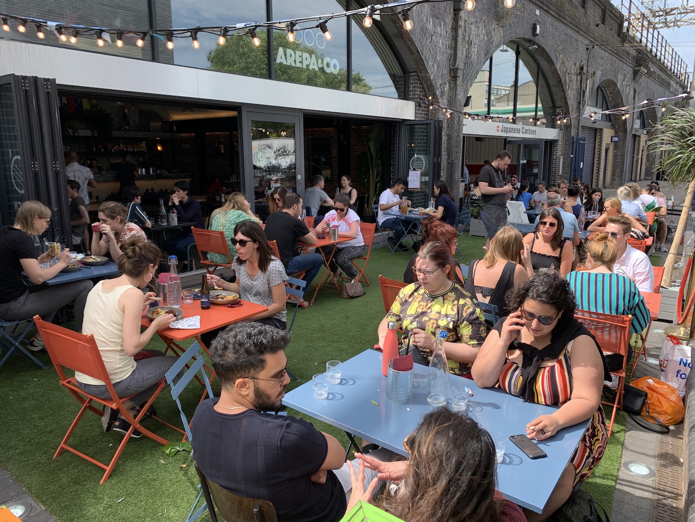 Outdoor terrace at Arepa & Co, vibrant networking event with colorful seating and greenery.