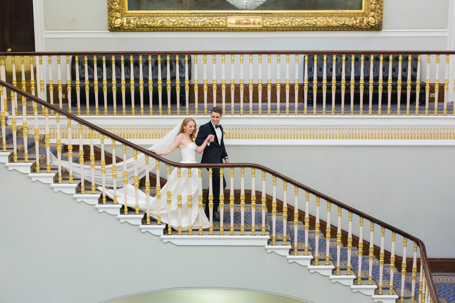 Elegant couple descending grand staircase at 116 Pall Mall wedding venue