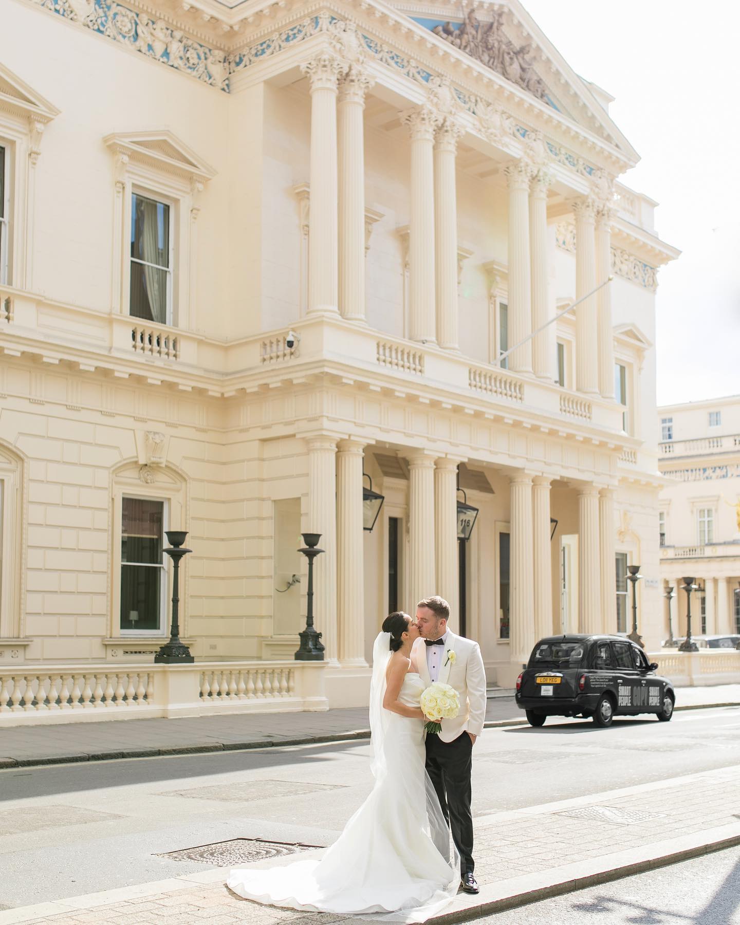 Newlyweds kiss outside elegant 116 Pall Mall wedding venue, with classic architecture.