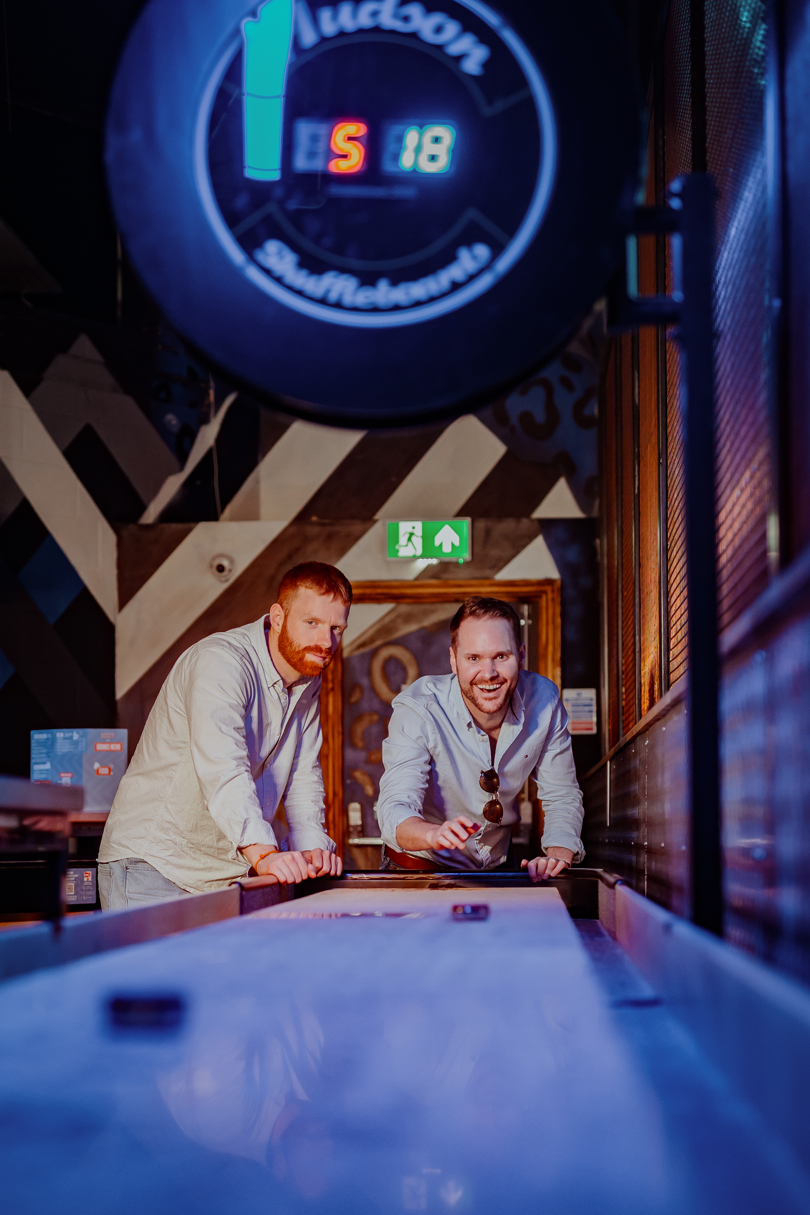 Engaged couple at shuffleboard table in Roxy Lanes, perfect for social events.