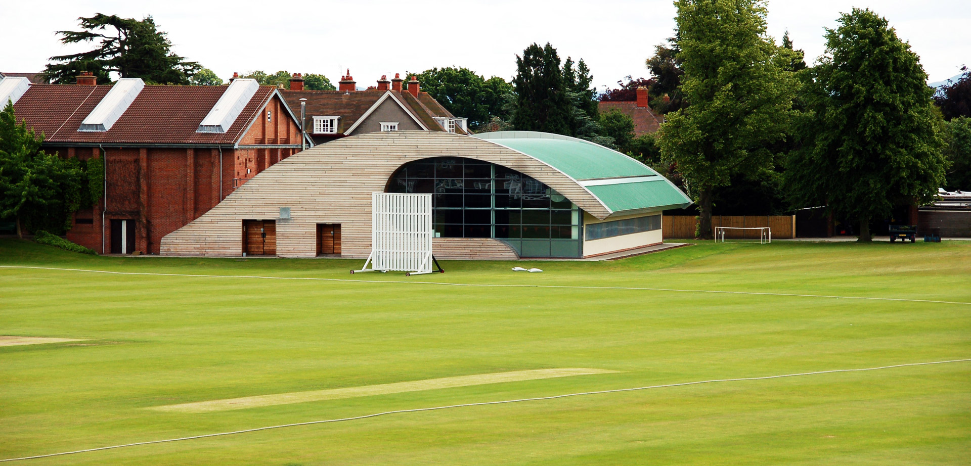 Modern pavilion at Shrewsbury School cricket pitch for corporate retreats and outdoor networking.