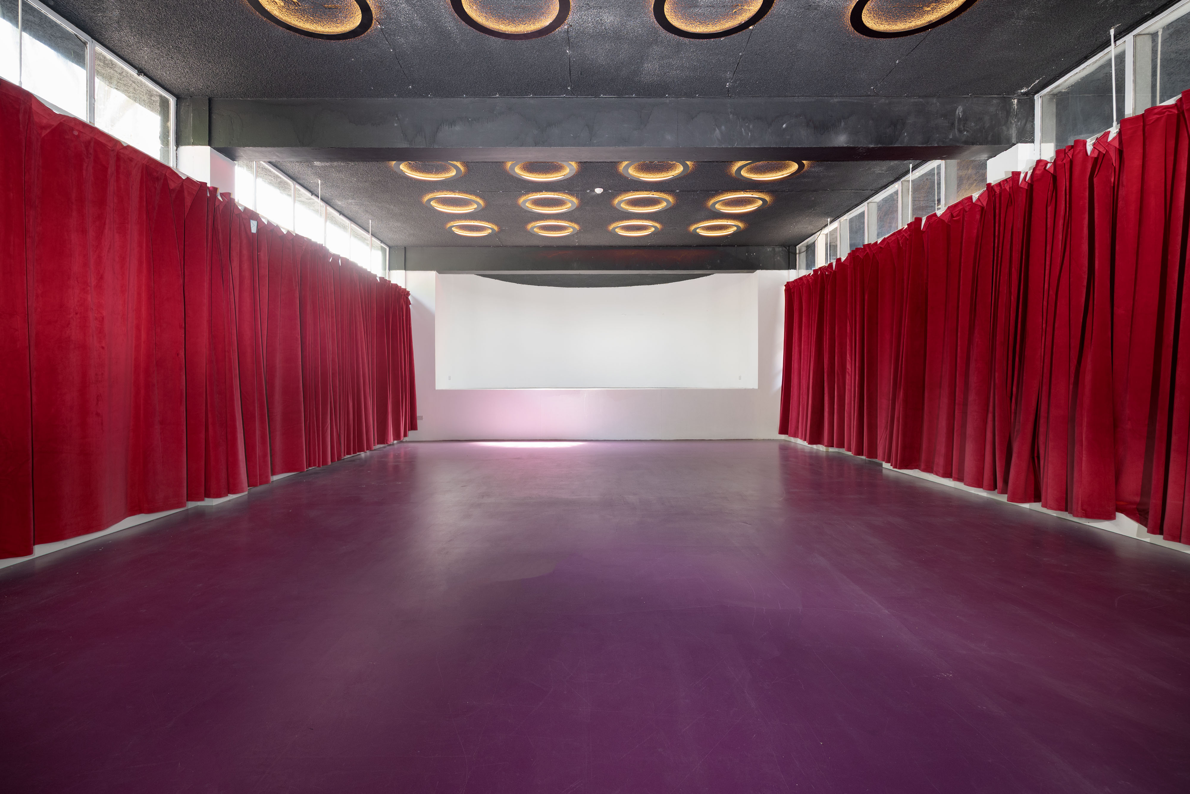Versatile event space with red curtains, ideal for conferences and social gatherings.