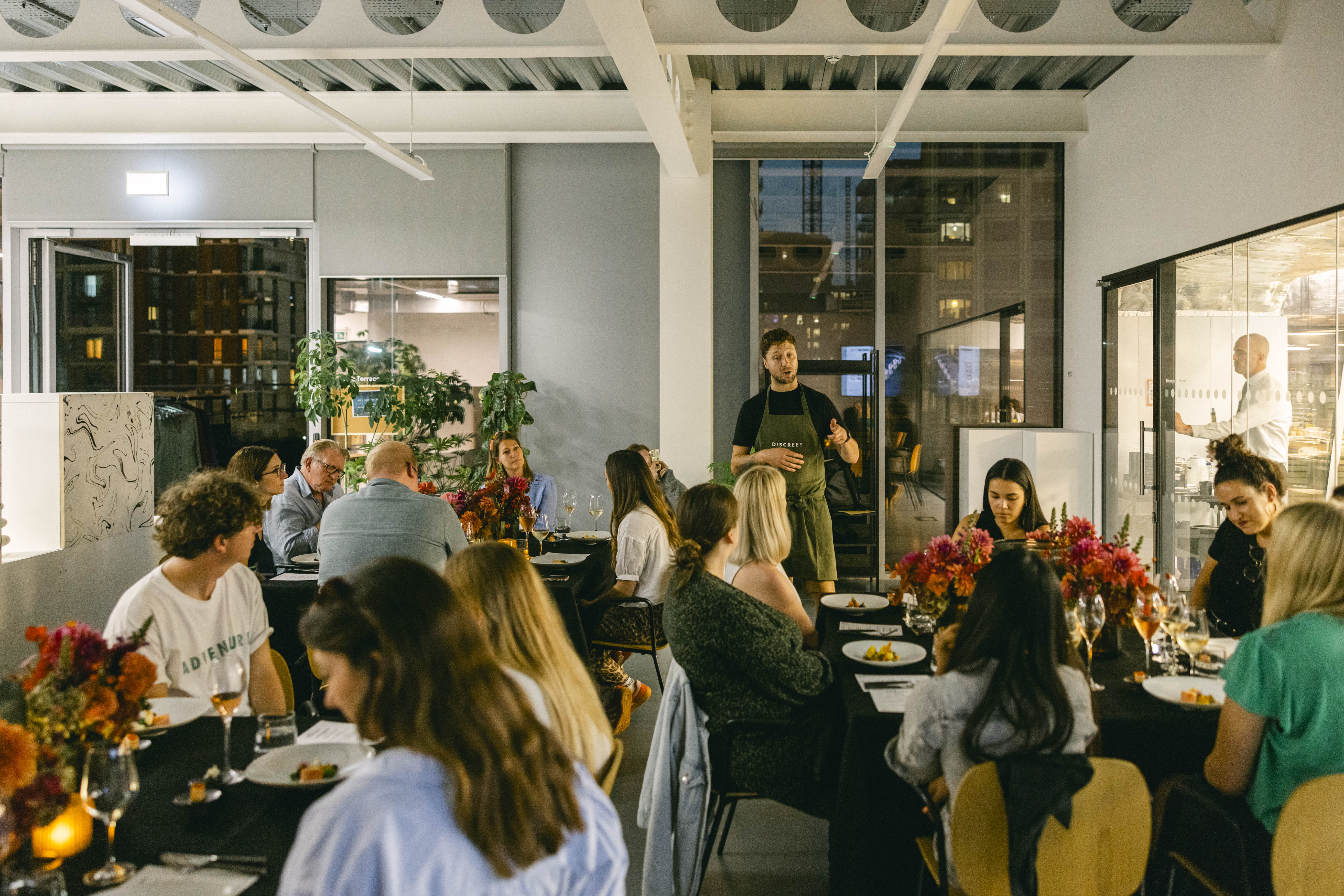 Intimate dinner event in Glass Room, Mission Kitchen with elegant table settings and engaged guests.