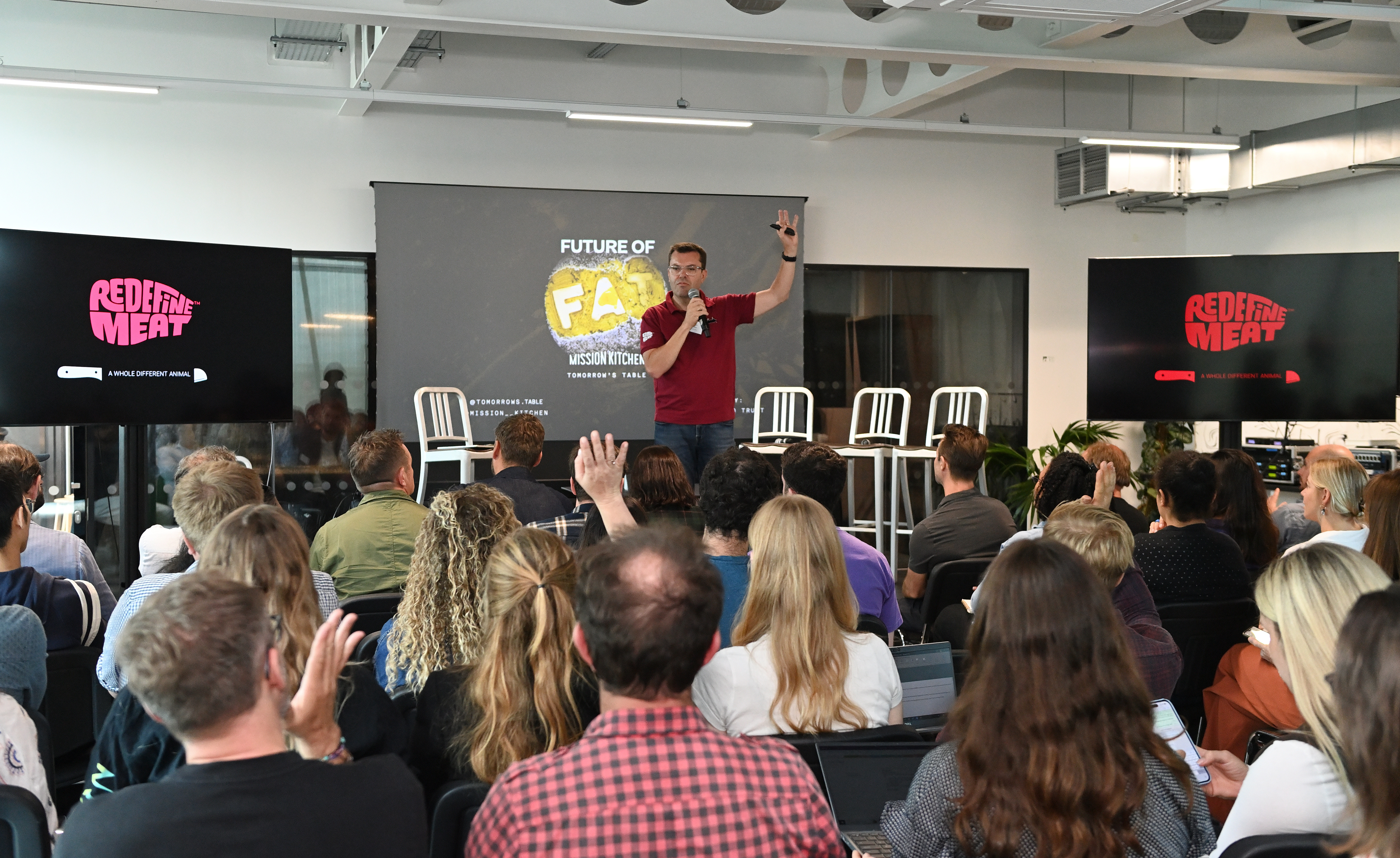 Dynamic speaker engaging audience in modern Glass Room at Mission Kitchen event.