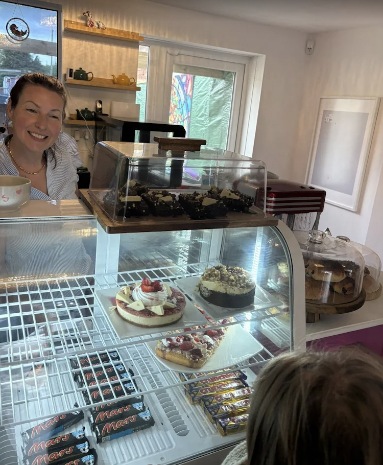 Friendly barista serving desserts in cozy Canine Cuddle Cafe, perfect for events and meetings.