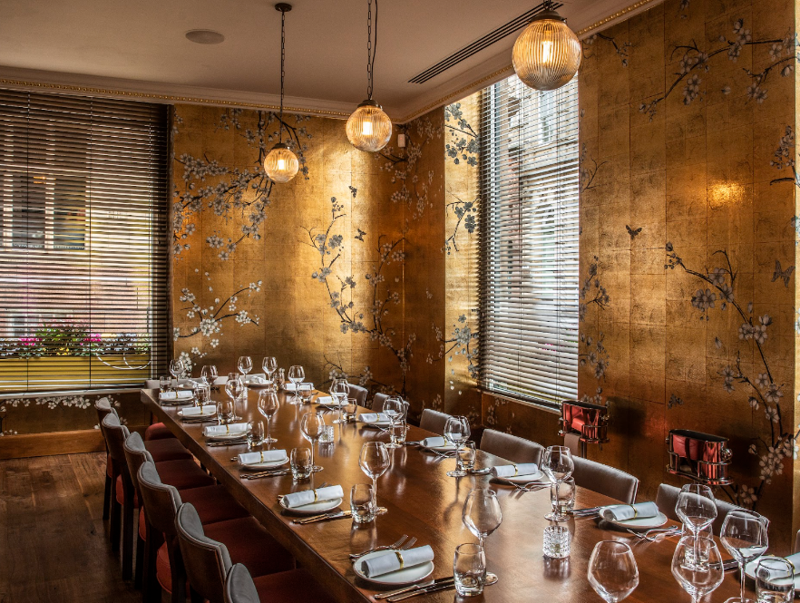 Private dining room with gold-leaf walls for luxury board dinners and corporate events.