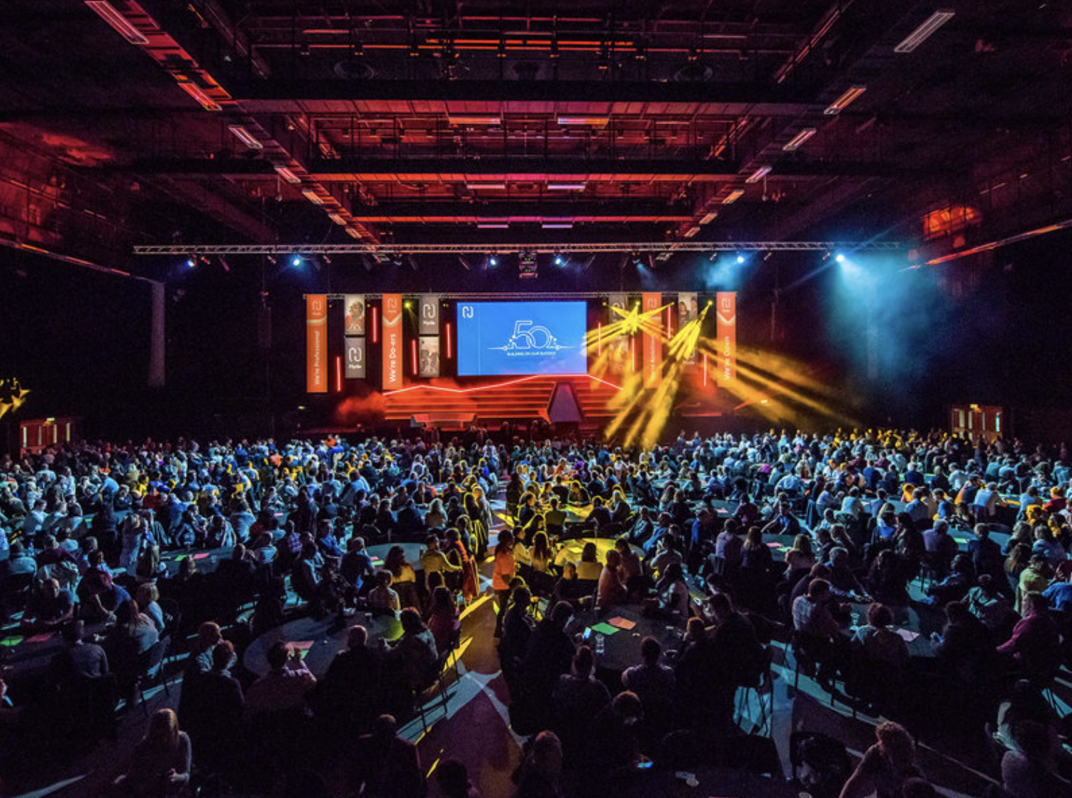 Brighton Centre venue with vibrant lighting and packed audience at a large event.