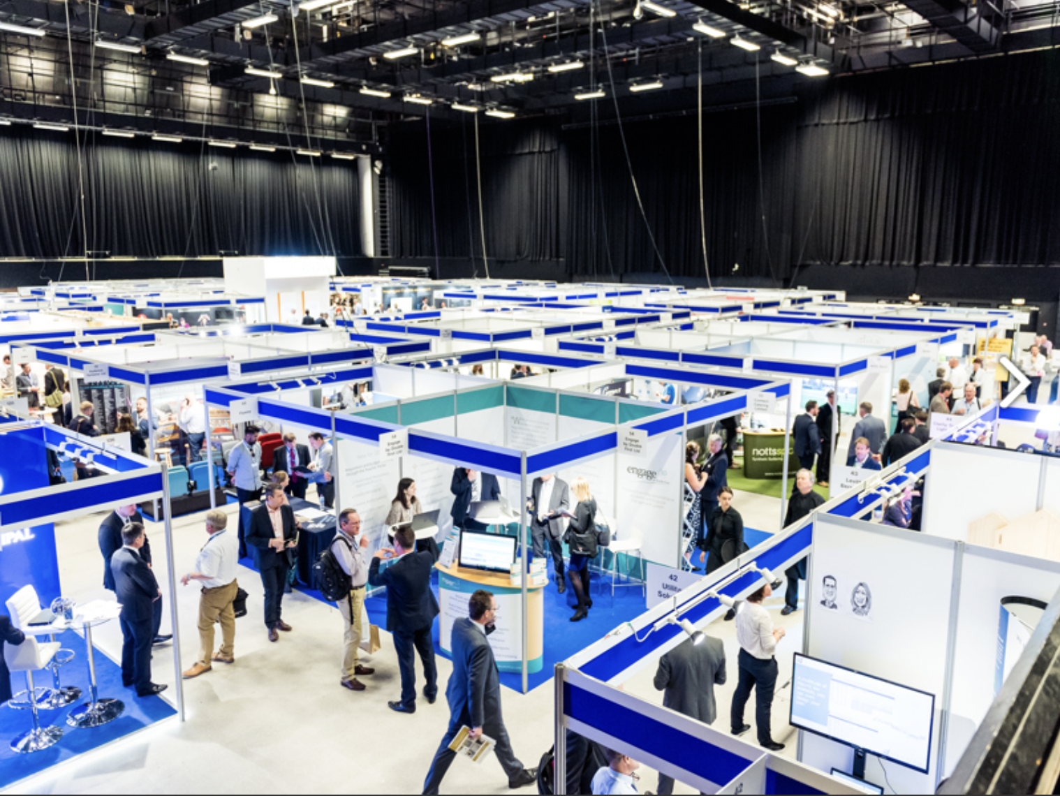 Brighton Centre exhibition hall bustling with vendors and attendees at a networking event.