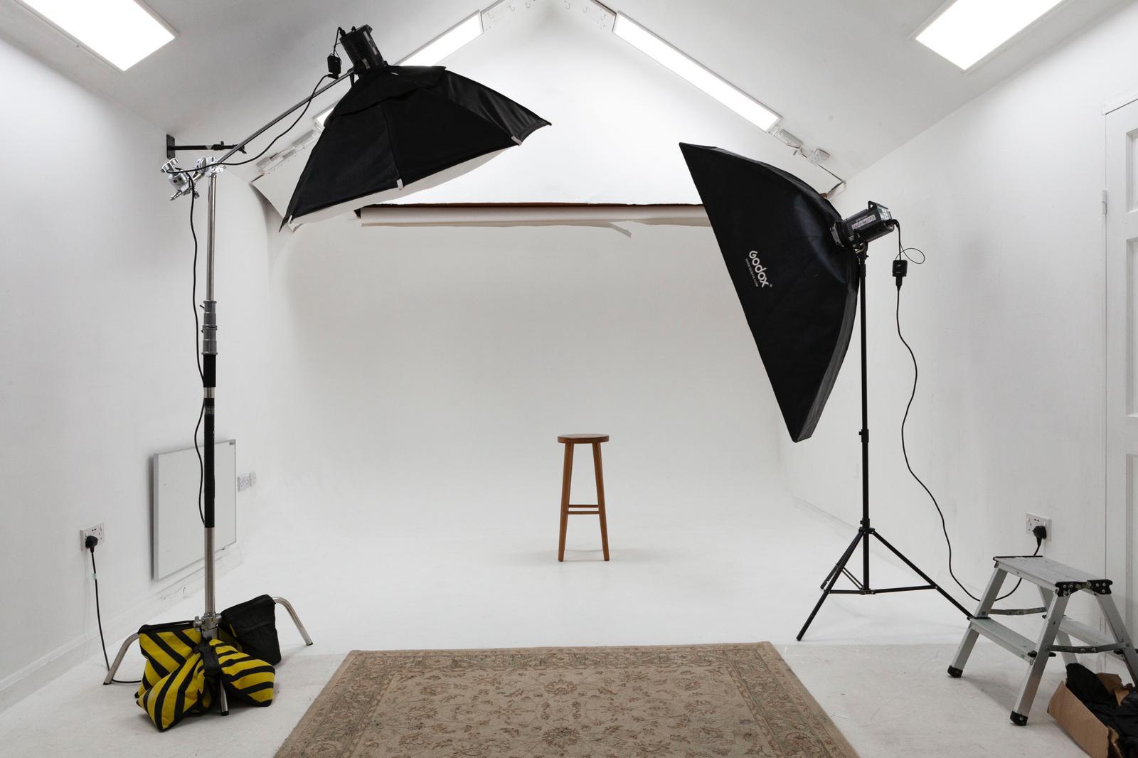 All-white photography studio with lighting, perfect for professional shoots and events.
