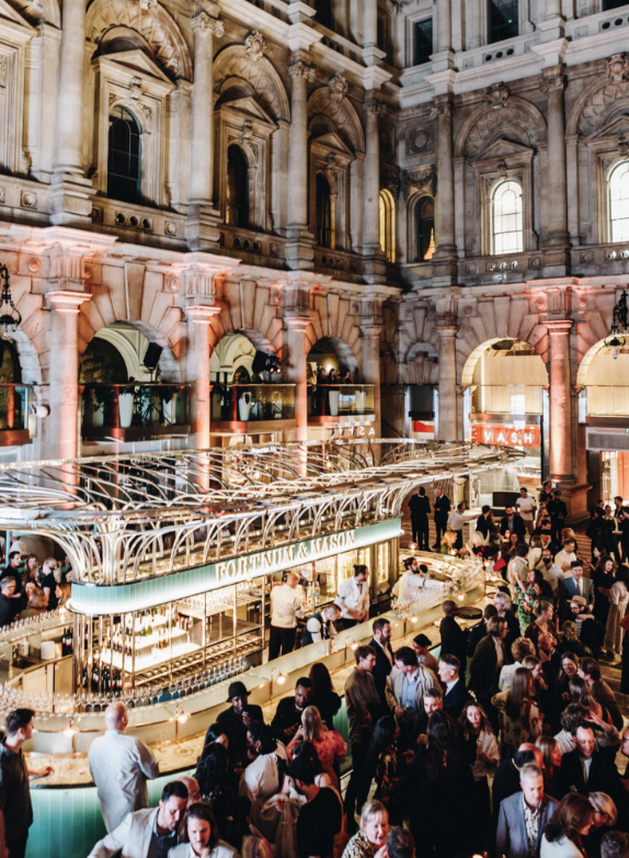Upscale networking event at Fortnum, elegant bar with vibrant crowd at The Royal Exchange.