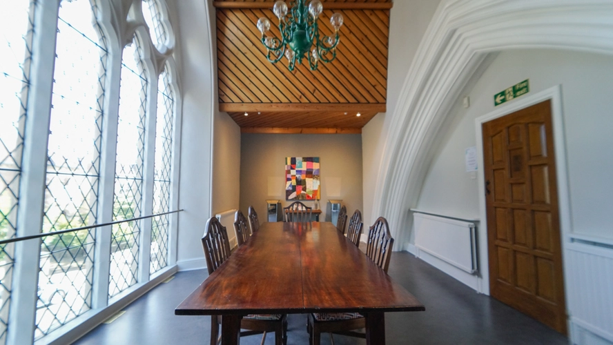 Spacious conference room with wooden table and elegant chandelier for meetings and workshops.