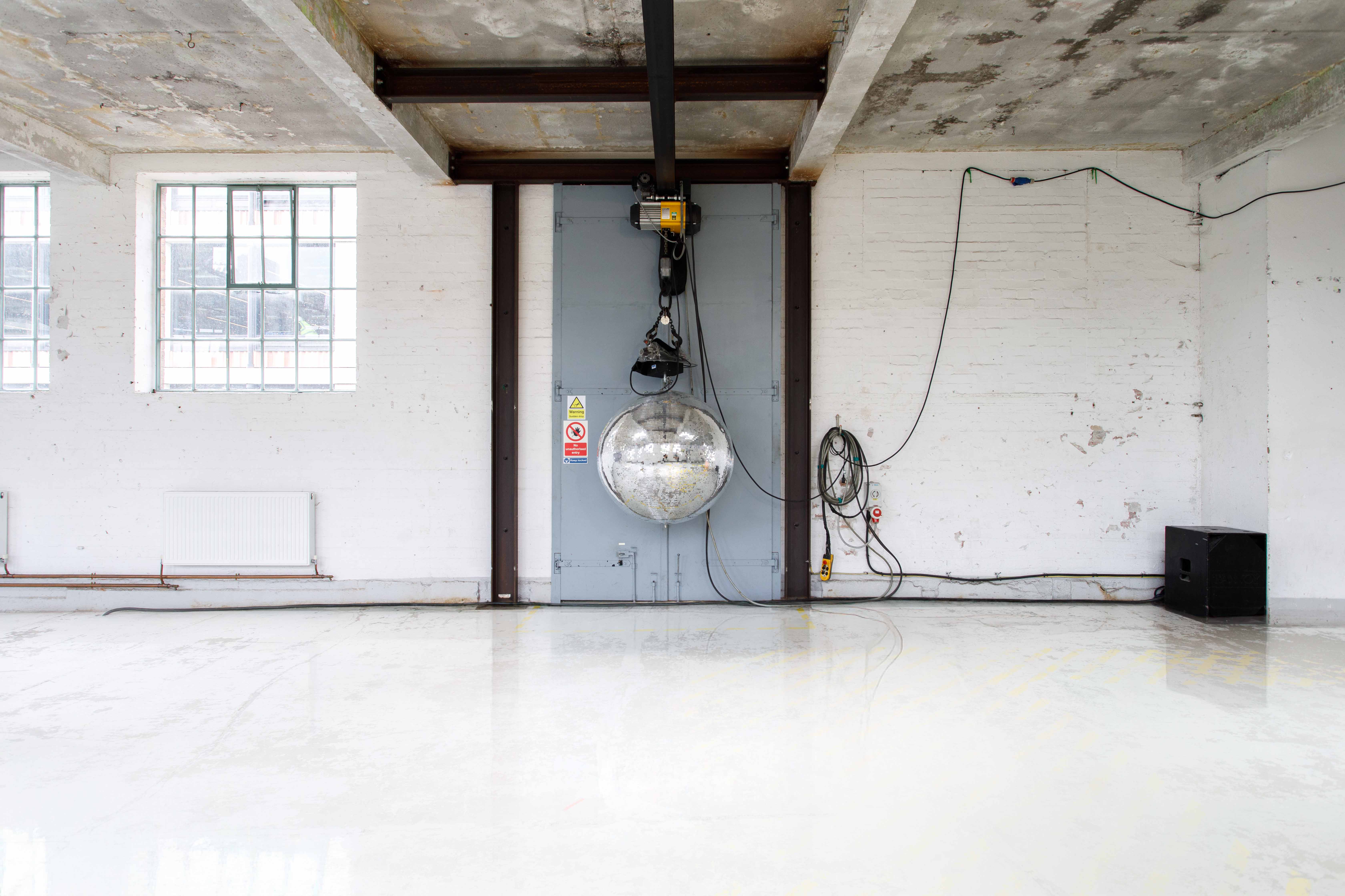 Empty industrial event space with concrete floors, ideal for creative workshops and events.