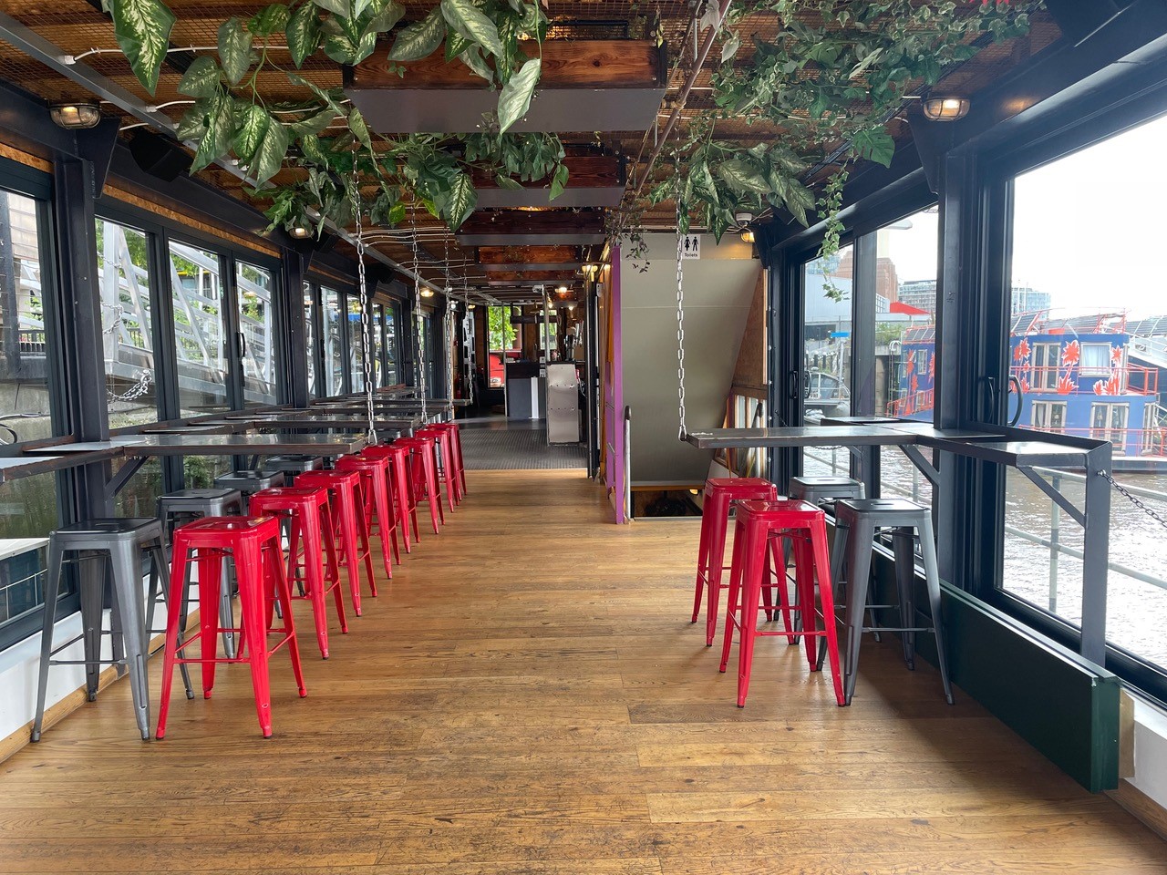 Indoor Middle Deck of Battersea Barge: modern event space with red stools and greenery.