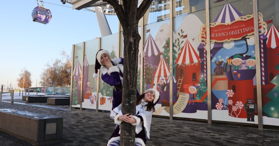 "Christmas party performers near a decorated tree at IFS Cloud Cable Car, London."