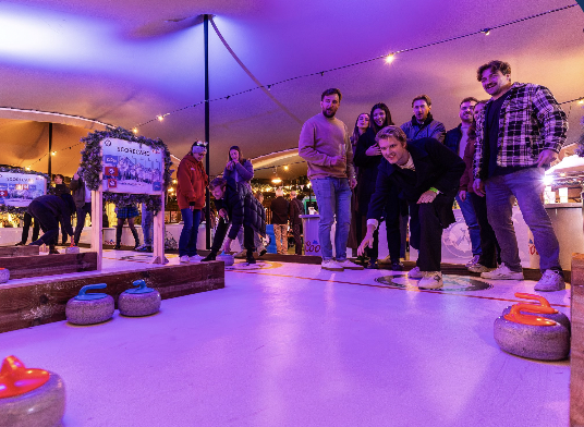 "Lively curling game at Exclusive Venue Hire in Chelsea Winter Village for team building."