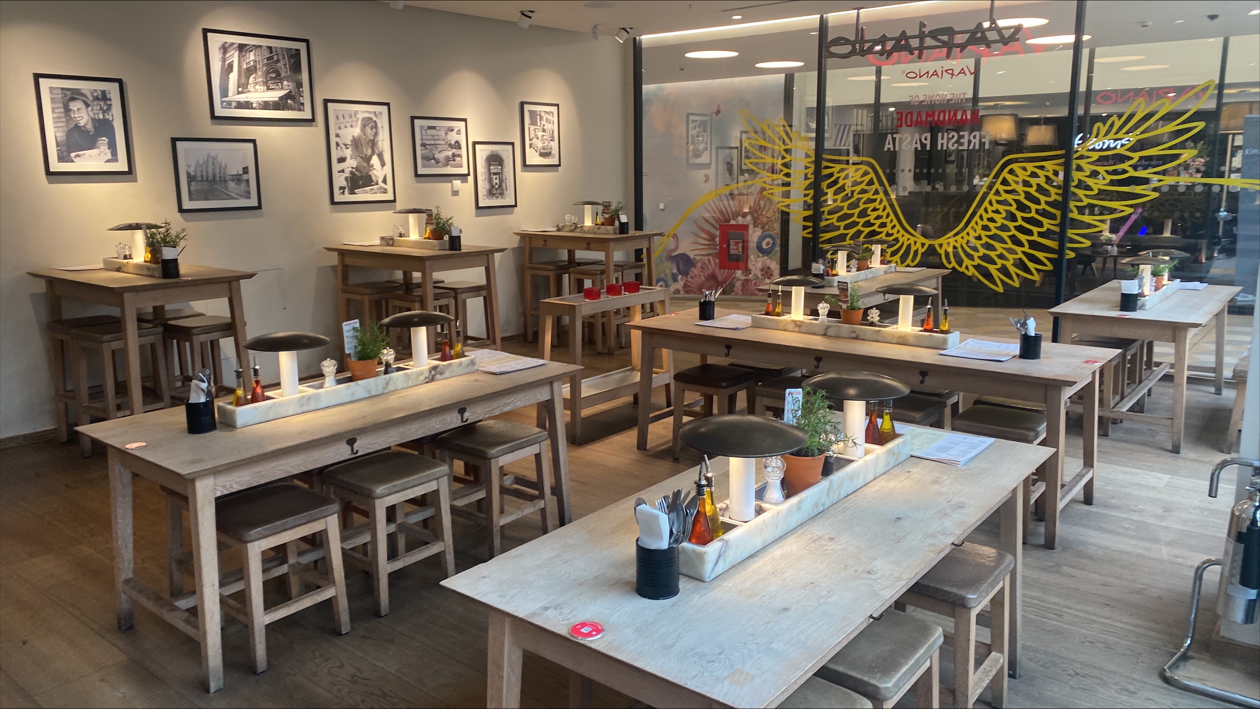 Full venue hire at Vapiano Manchester, featuring rustic wooden tables for events.