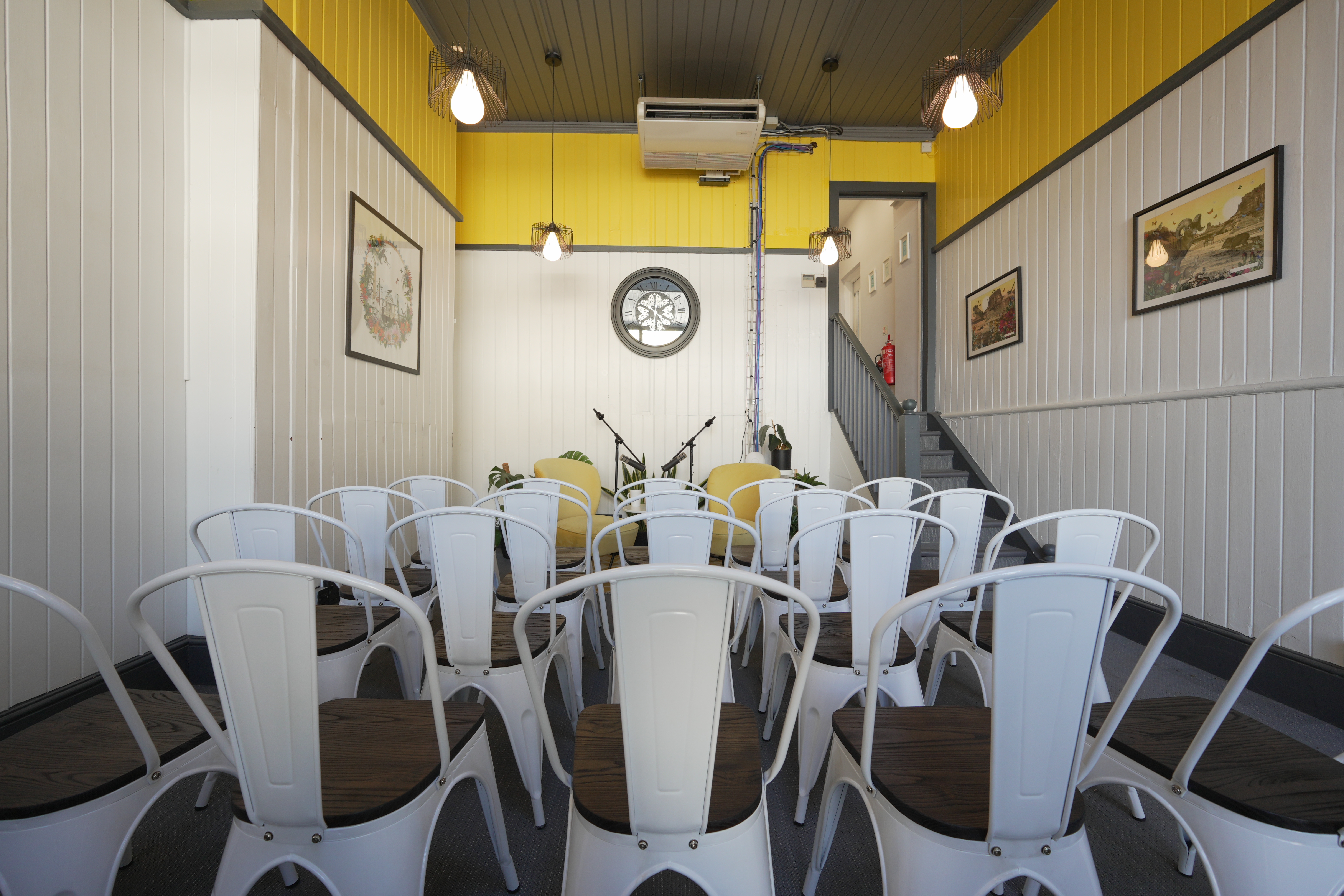 Intimate event space with white chairs and yellow decor for networking or workshops.