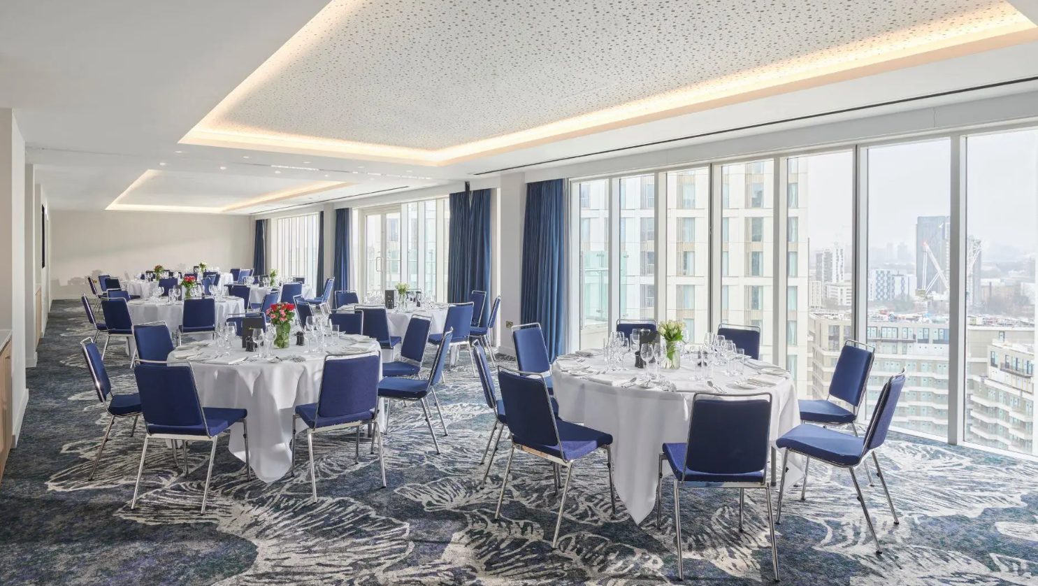 Elegant Glasshouse event space with white tables, ideal for corporate meetings and receptions.