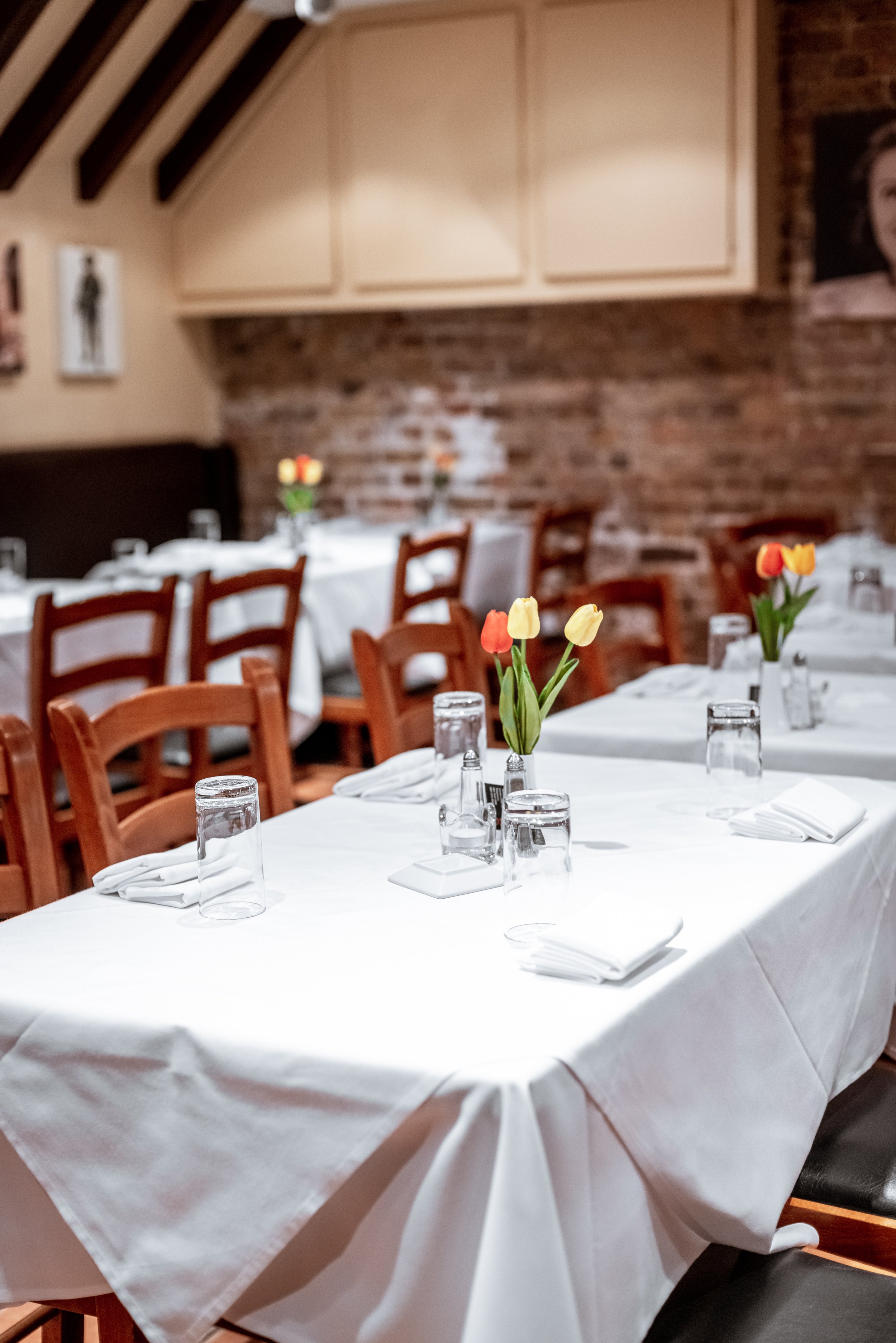 Elegant dining setup with white tablecloths and tulip centerpieces for intimate events.