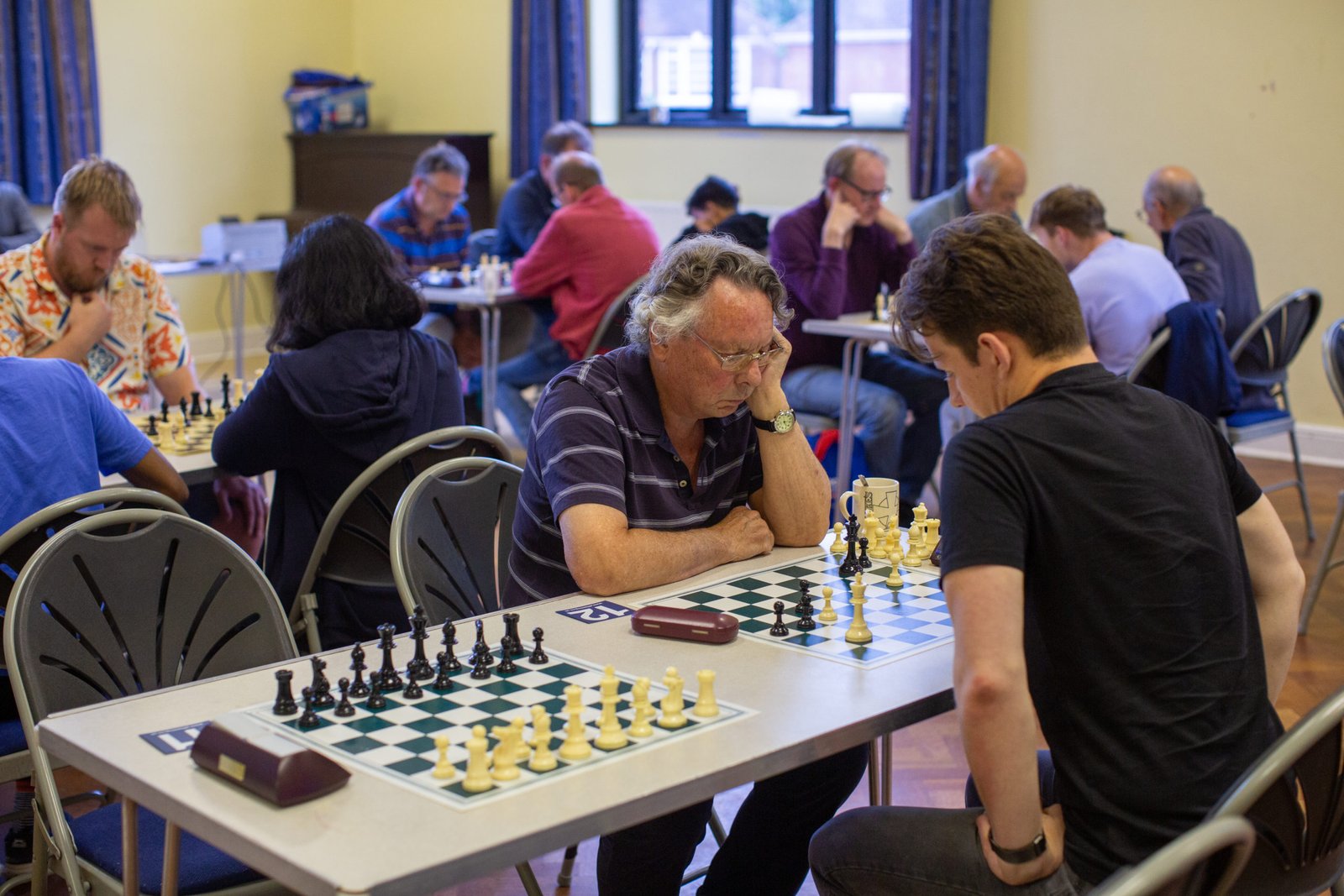 Alt text: Chess tournament at St Luke's Community Hall with bright natural lighting and organized setup.