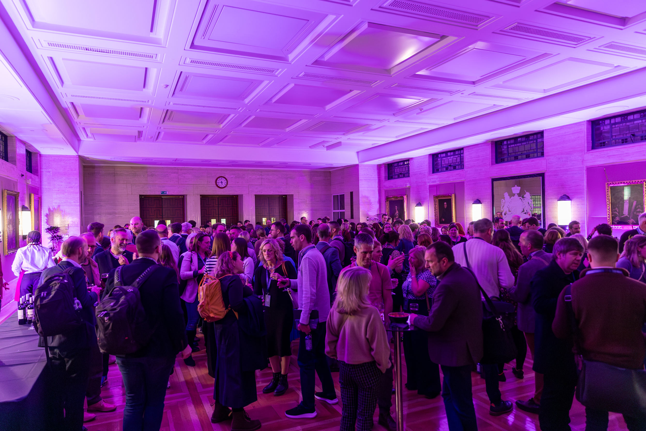 "Networking event in Beveridge Hall's Main Hall with elegant purple lighting"