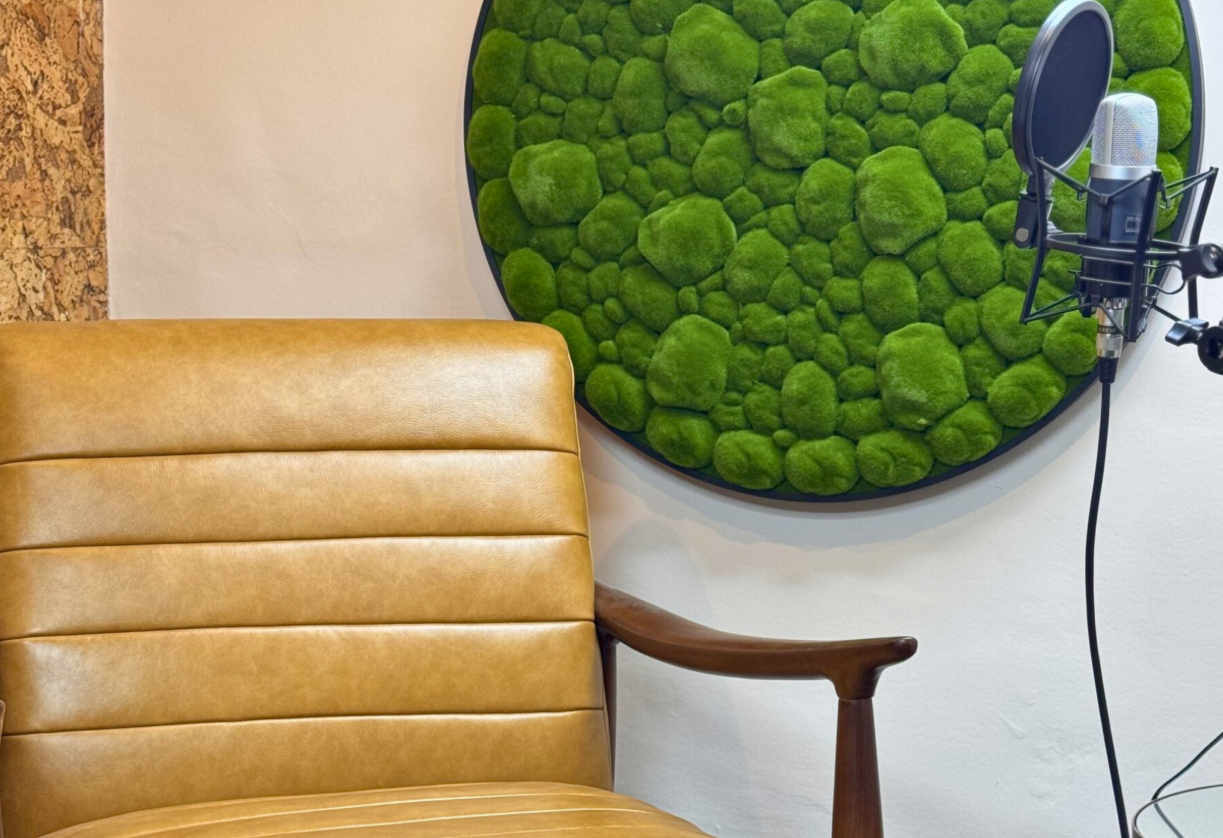 Cozy podcast studio with leather chair and moss wall art for intimate discussions.